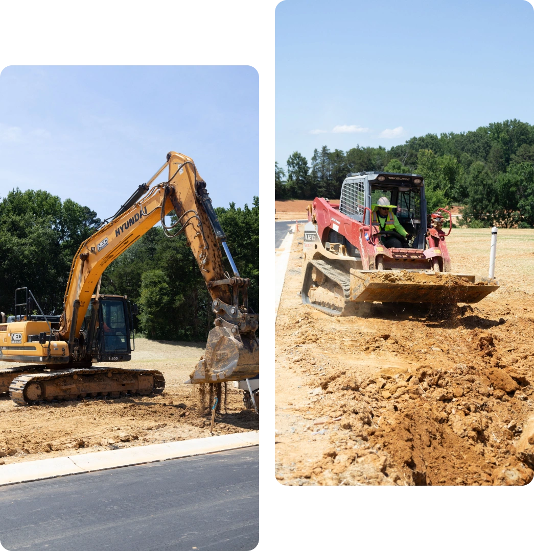 Construction vehicles working on a dirt road under clear skies.